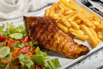Grilled chicken. Grilled chicken breast with salad and fries on a white background