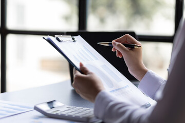 Businesswoman doing paperwork in the office analyzing financial charts and accounting budget.