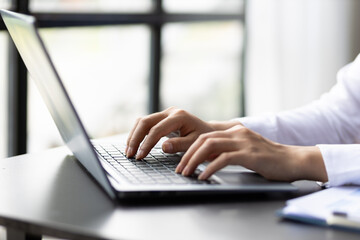 Woman typing on laptop keyboard.