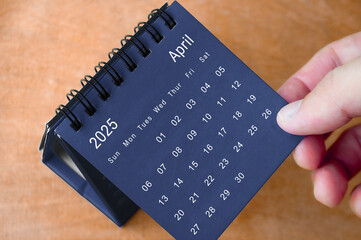 April 2025 black and white calendar on wooden desk. Calendar and new month concept
