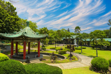 Serene Asian-Influenced Park with Red Pavilion, Pond, and Lush Greenery in a Tropical Setting