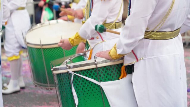 A group of drummers playing rhythmic sambo music during a carnival procession close-up dressed in colorful traditional suits.