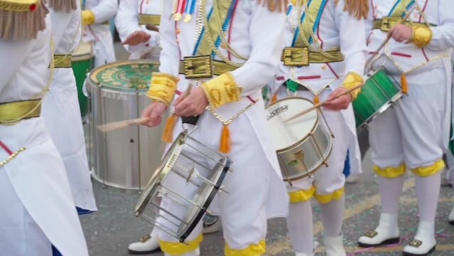 A group of drummers playing rhythmic sambo music during a carnival procession close-up dressed in colorful traditional suits.