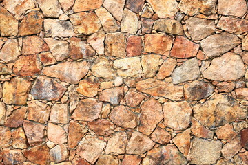 a yellow beige natural stone wall of different sized stones, traditional crafts