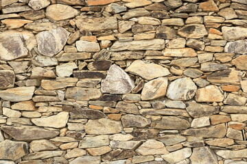 a yellow beige natural stone wall of different sized stones, traditional crafts