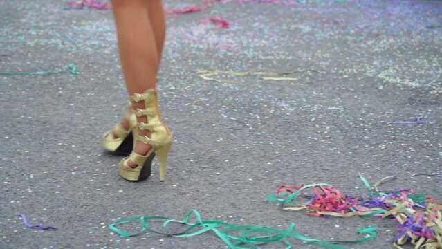 Women's graceful legs in suits and beautiful shoes dancing the samba at a fun carnival parade in slow motion and confetti on the floor. Close-up.