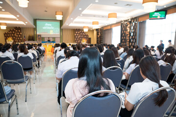 Rearview of university students attending academic conference presentations in the auditorium.
