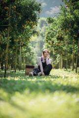 Fototapeta premium A happy woman farmer is resting in orchard or orange farm.