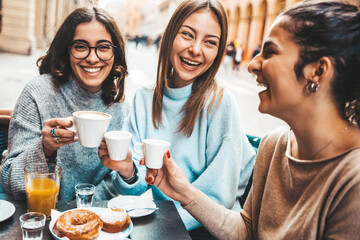 Three young women enjoying breakfast drinking coffee sitting at bar cafeteria - Life style concept with female friends hanging out on city street - Food, beverage and friendship concept - obrazy, fototapety, plakaty