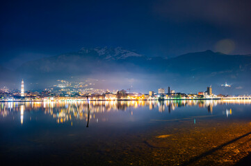 Naklejka premium The city of Lecco, with its lakeside promenade and its buildings, photographed in the evening in winter.