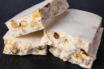 Pieces of soft hazelnut nougat on a dark slate surface.