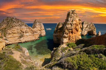 Sunset at Algarve Coast, Majestic Limestone Cliffs Rising from Turquoise Waters with Leisure Boat