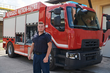 A confident firefighter strikes a pose in front of a modern firetruck, exuding pride, strength, and preparedness for emergency response