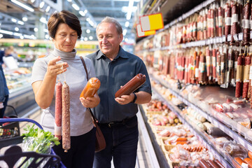 Elderly man and elderly woman choose sausage