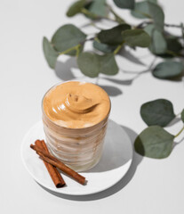 Whipped Dalgona coffee. Instant cold coffee with ice in a glass with cinnamon sticks on light background