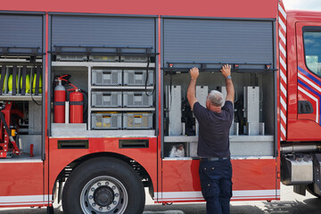 A dedicated firefighter preparing a modern firetruck for deployment to hazardous fire-stricken...