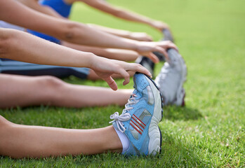 Stretching legs, sneakers and exercise in park, grass and nature with fitness group for health and...