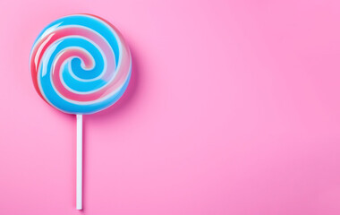 Pink and blue lollipop swirl on a white stick on a pink background. Top view, copy space