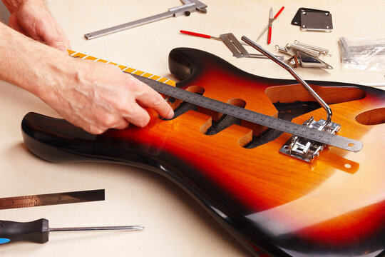 Guitar master measures distance of tremolo installation on electric guitar.