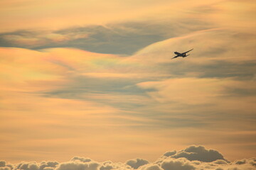 taking off airplane in front of iridescent clouds