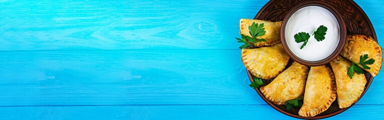 Delicious baked empanadas on wooden background. Top view. Banner.