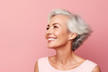 Smiling senior woman. Portrait of beautiful mature woman looking away and smiling while standing against pink background