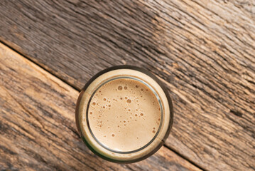Top view of a dark beer in a glass on a wooden bar top.