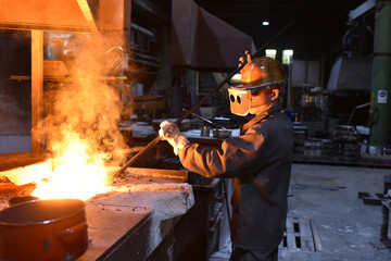 young worker in protective clothing at work at the blast furnace in an iron foundry