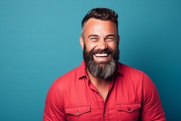 Portrait of a handsome man with beard and mustache laughing over blue background