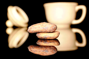 Several dry cocoa beans in a ceramic cup, macro, isolated on black background.