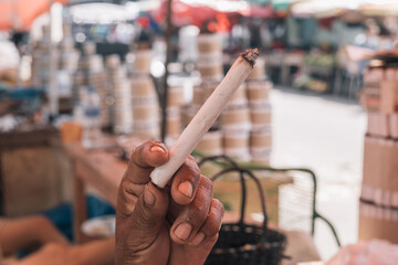 Hand of an unrecognizable person holding a freshly made handmade cigarette in the market of Iquitos Peru