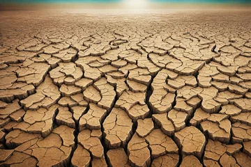 Foto op Canvas Dry land with cracked earth under blue sky background. © Cheetose