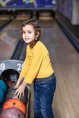 Fototapeta na wymiar Cute little kid girl with ball at bowling club