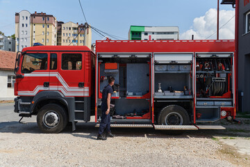 Fototapeta na wymiar A dedicated firefighter preparing a modern firetruck for deployment to hazardous fire-stricken areas, demonstrating readiness and commitment to emergency response