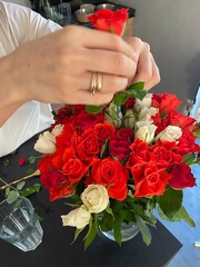 Female hands make a beautiful bouquet of red and white small roses