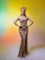 A beautiful, slender woman wearing a crown of seashells covered in gold. She's wearing a tight-fitting dress made of sparkly floats. On a yellow background