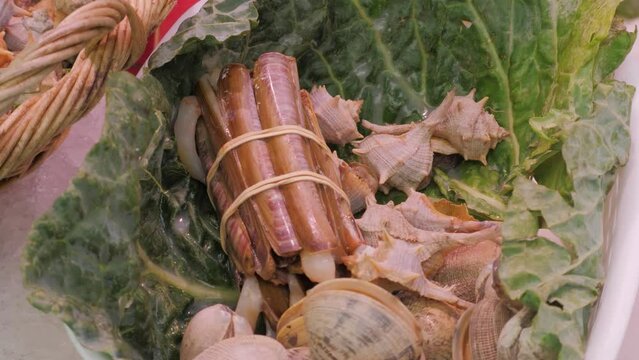 Fresh snails in a shell on green salad lettuce leaf. Street food. Sea food products on markets or bazaar