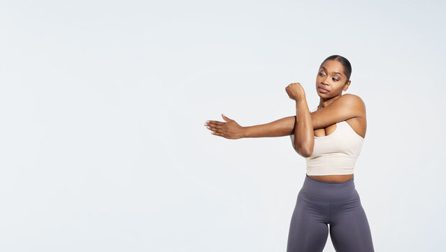 African american fitness lady exercising stretching arms before workout, studio