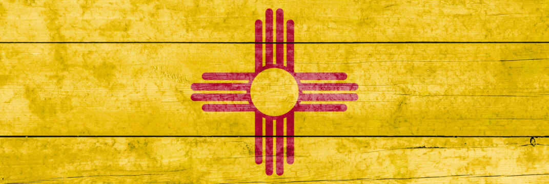 New Mexico State flag on a wooden surface. Banner of the grunge New Mexico State flag.
