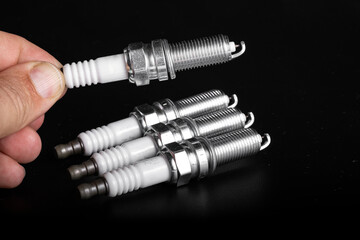 A new candle in a man's hand on a white background. The concept of choosing spark plugs.