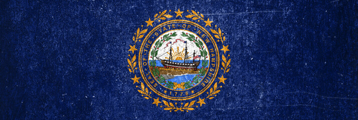 Close-up of the grunge New Hampshire State flag. Dirty New Hampshire State flag on a metal surface.