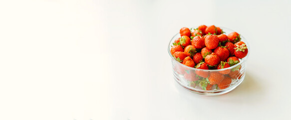 Banner size shot of a whole glass bowl of strawberries with white copy space aside.