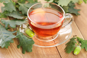 Oak bark tea with fresh acorns and leaves on wooden table, closeup, copy space, green medicine,...