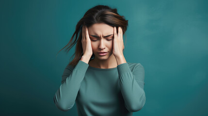 Woman with closed eyes and a pained expression is holding her head with both hands