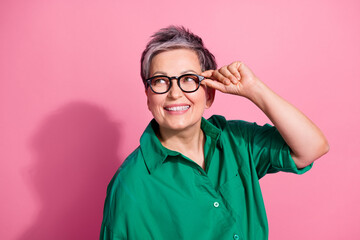 Photo portrait of attractive pensioner woman look empty space touch specs wear trendy green clothes...