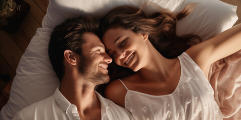 A happy couple man and woman lying on a bed and smiling at each other. High quality photo