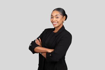 Confident African American businesswoman with a charming smile stands with arms crossed