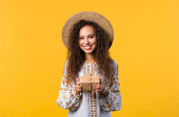 Pretty woman, curly hair with gift box on yellow background. Happy with present.