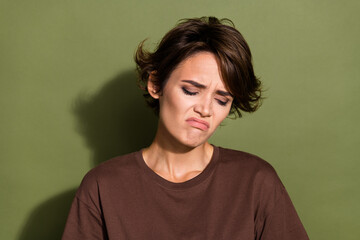 Portrait of gloomy sad unhappy girl with short hairstyle wear oversize t-shirt look down crying isolated on green color background