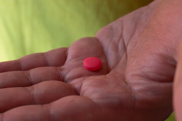 Close-up of a single red pill in the palm